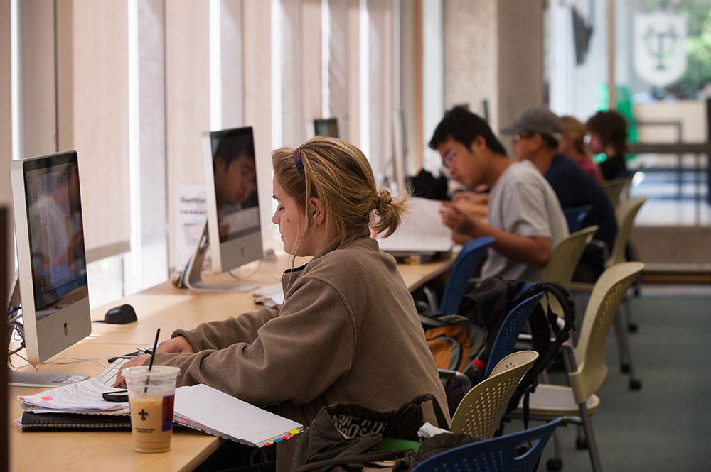 Students sit in a computer lab on campus and study. 